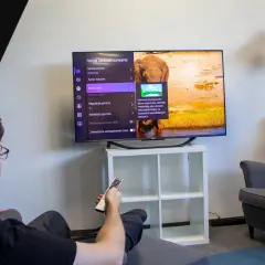 Mężczyzna siedzi w fotelu i ogląda telewizor z menu ustawień obrazu.